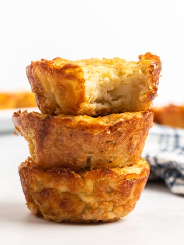 Stack of 3 potato latke muffins with a bite showing the inside.