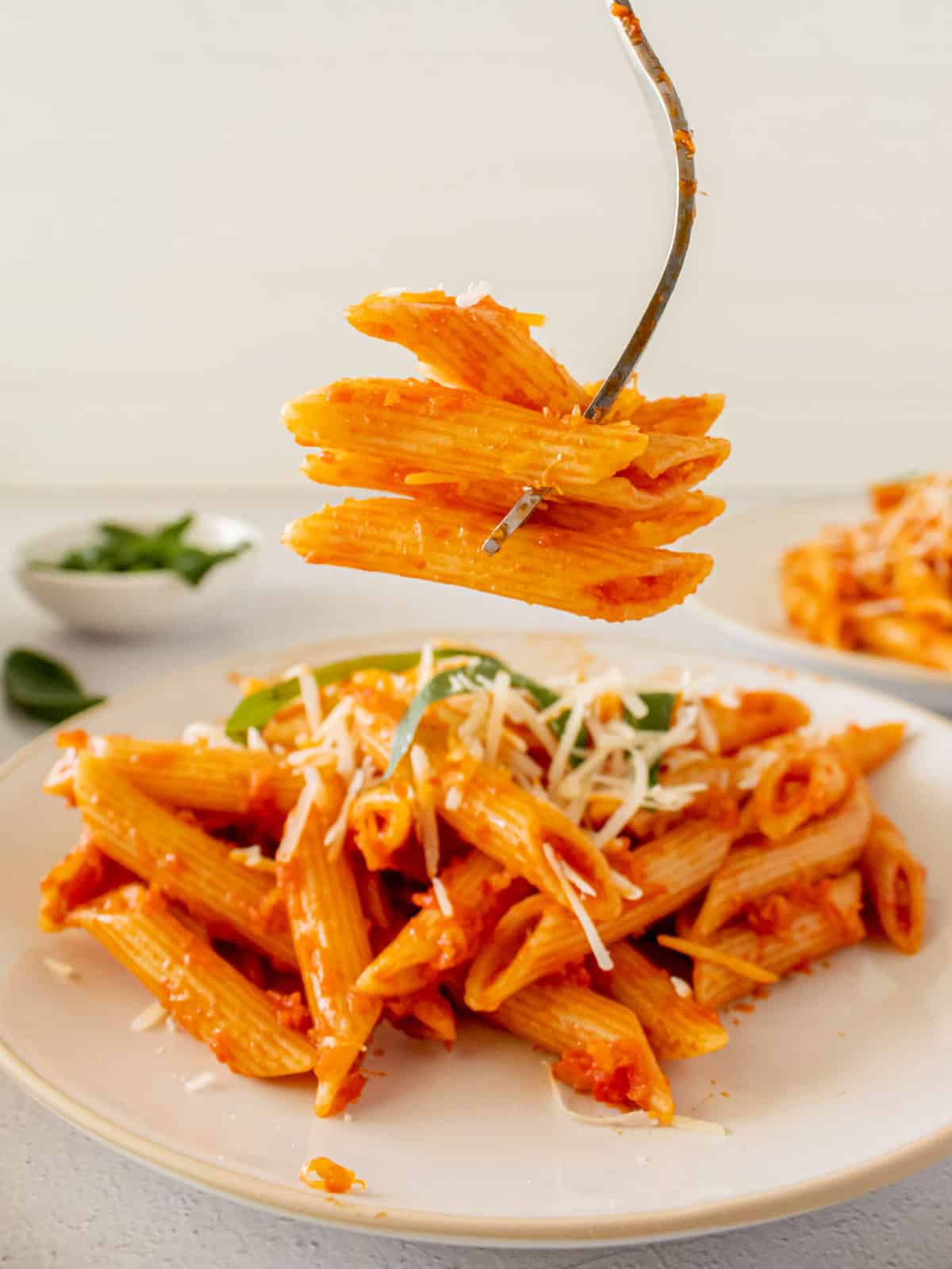 A forkful of penne pasta with tomato and vegetable sauce.