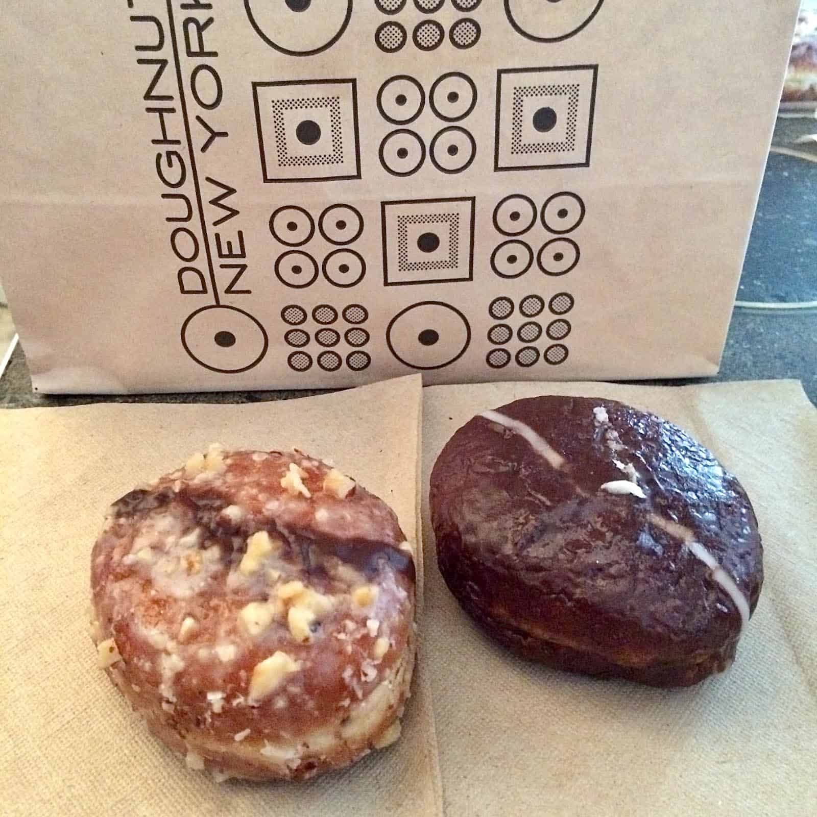 Two doughnuts from Doughnut Plant NYC next to bag.