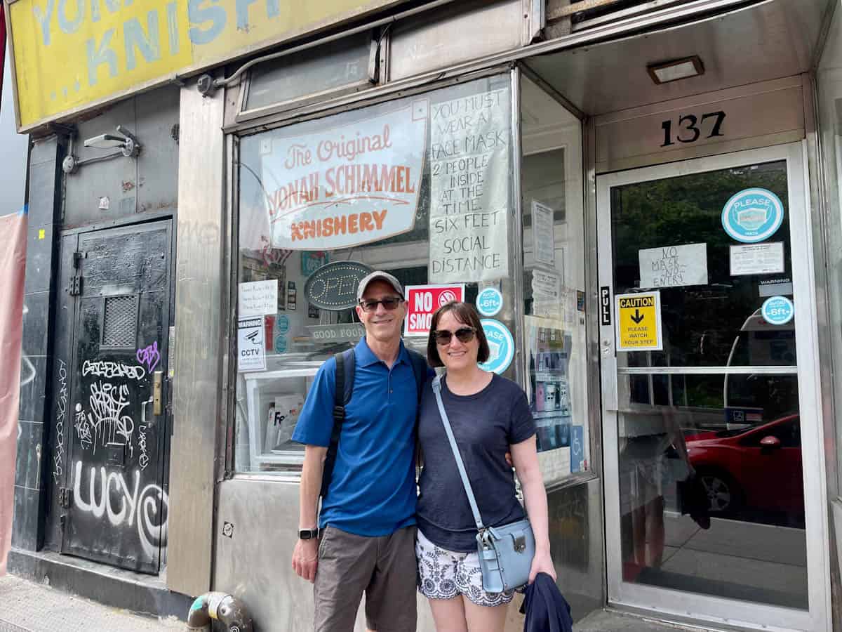 Two people standing in front of Yonah Schimmel's Knishery on Houston Street.