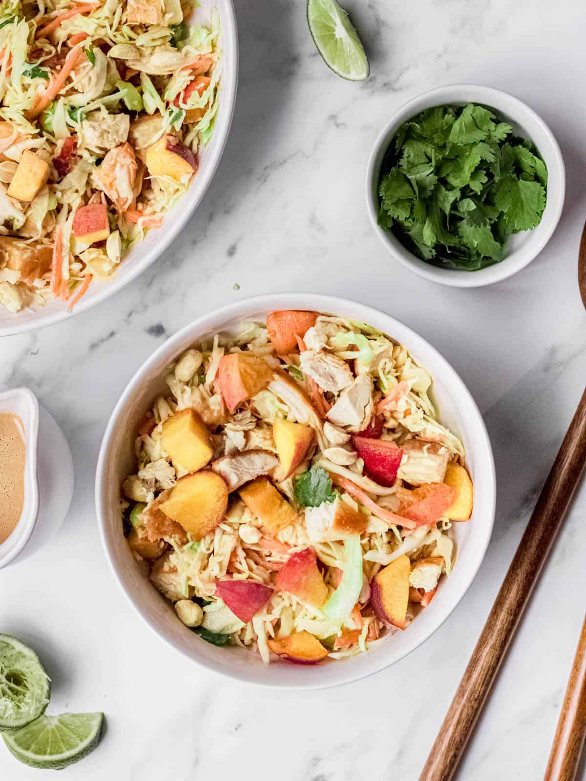 Thai chicken salad with peaches, lime, and cilantro served in a bowl.