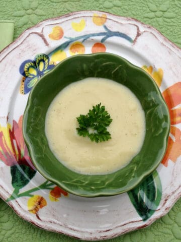Bowl of cauliflower soup on top of a decorative plate.