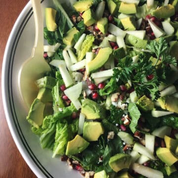 Fall Harvest Salad in a bowl with apples, pomegranate, avocado, lettuce, pecans.