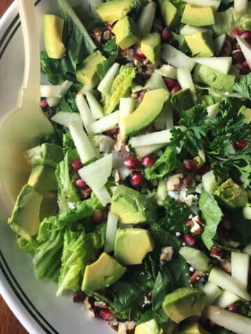 Fall Harvest Salad in a bowl with apples, pomegranate, avocado, lettuce, pecans.