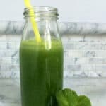Green juice in glass bottle with straw.