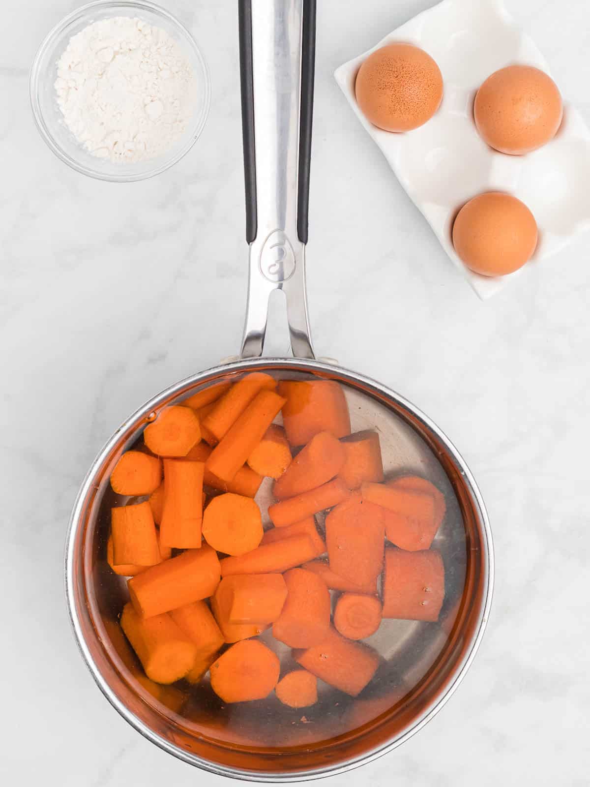 Cut carrots cooking in a pot of boiling water.