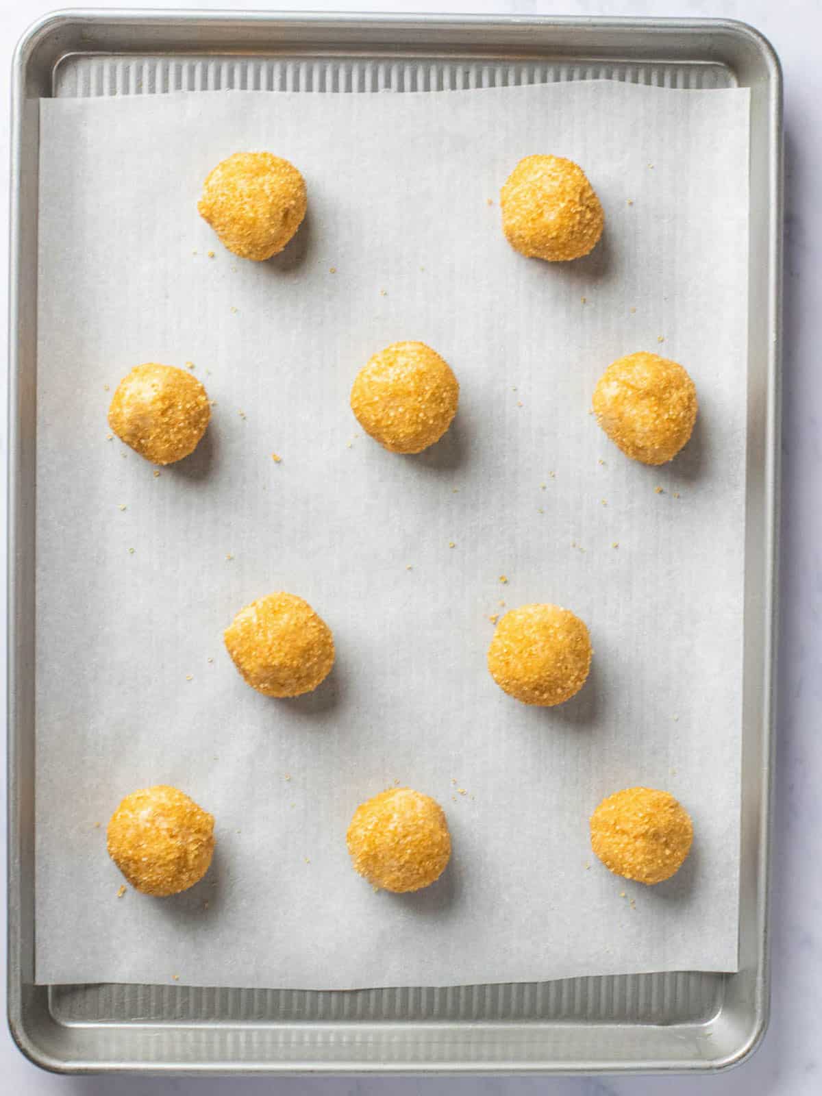 Honey cookie batter rolled into balls and placed on baking sheet with parchment.