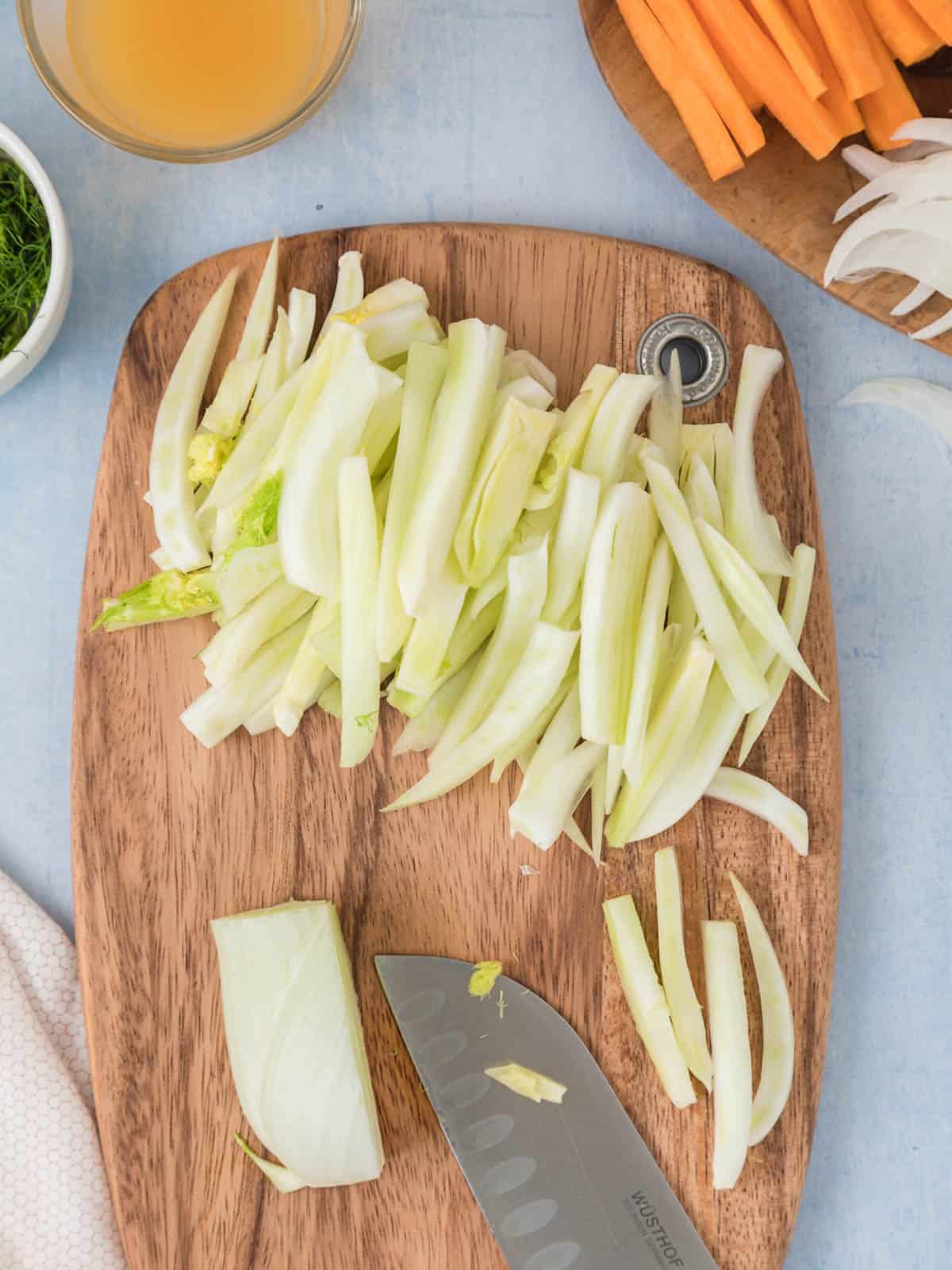 Julienne cut fennel on a cutting board.