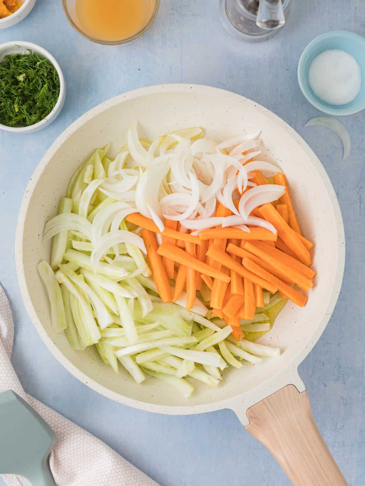 Sliced onion, fennel, and carrot in a pan ready for cooking.