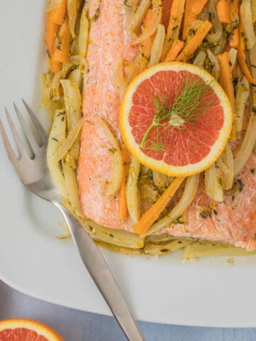 Baked whole salmon topped with orange and veggies.