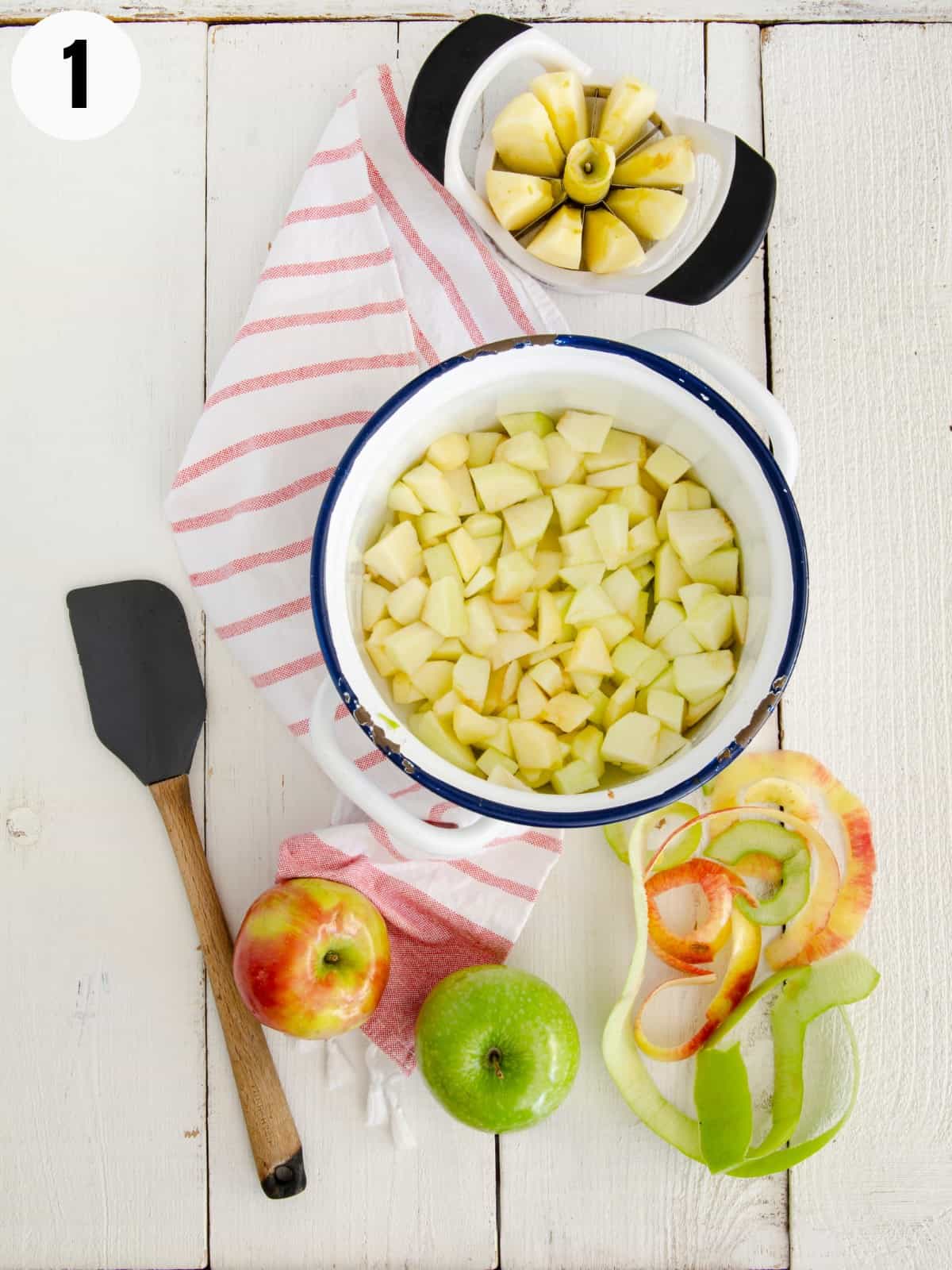 Apples in a pot with apples and peelings next to it.