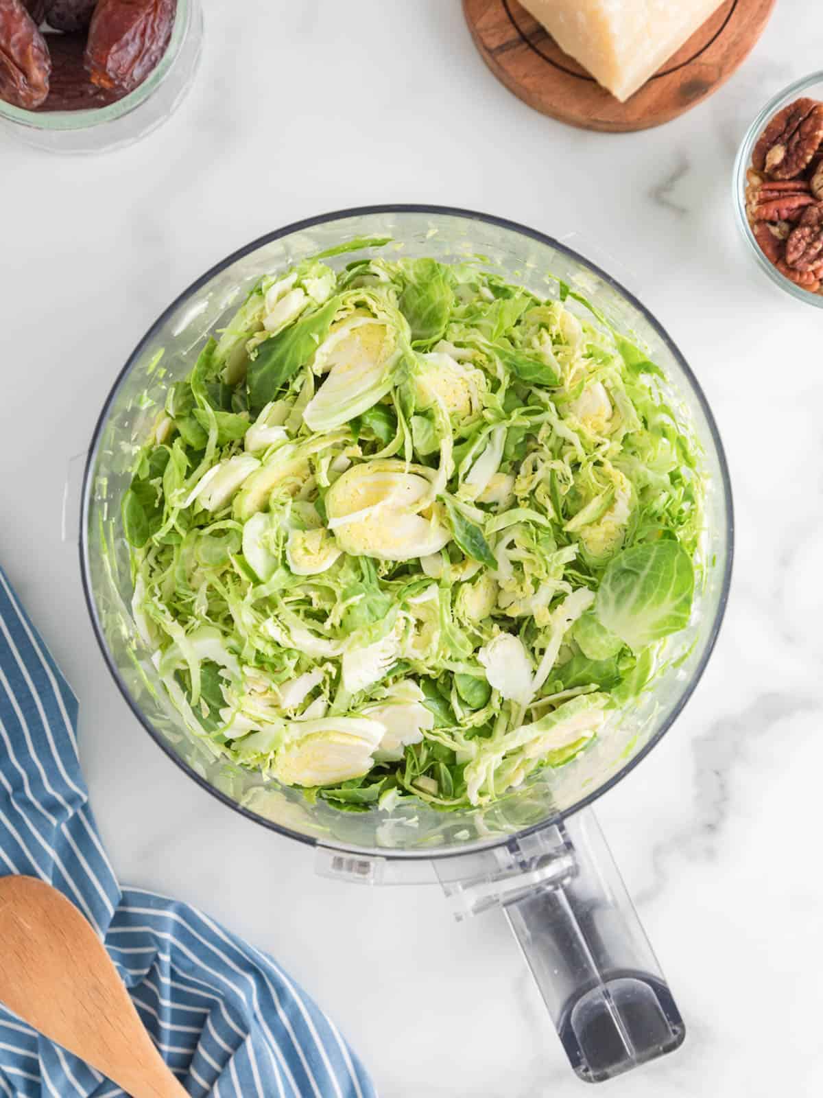 Shaved or shredded Brussels sprouts in food processor bowl.