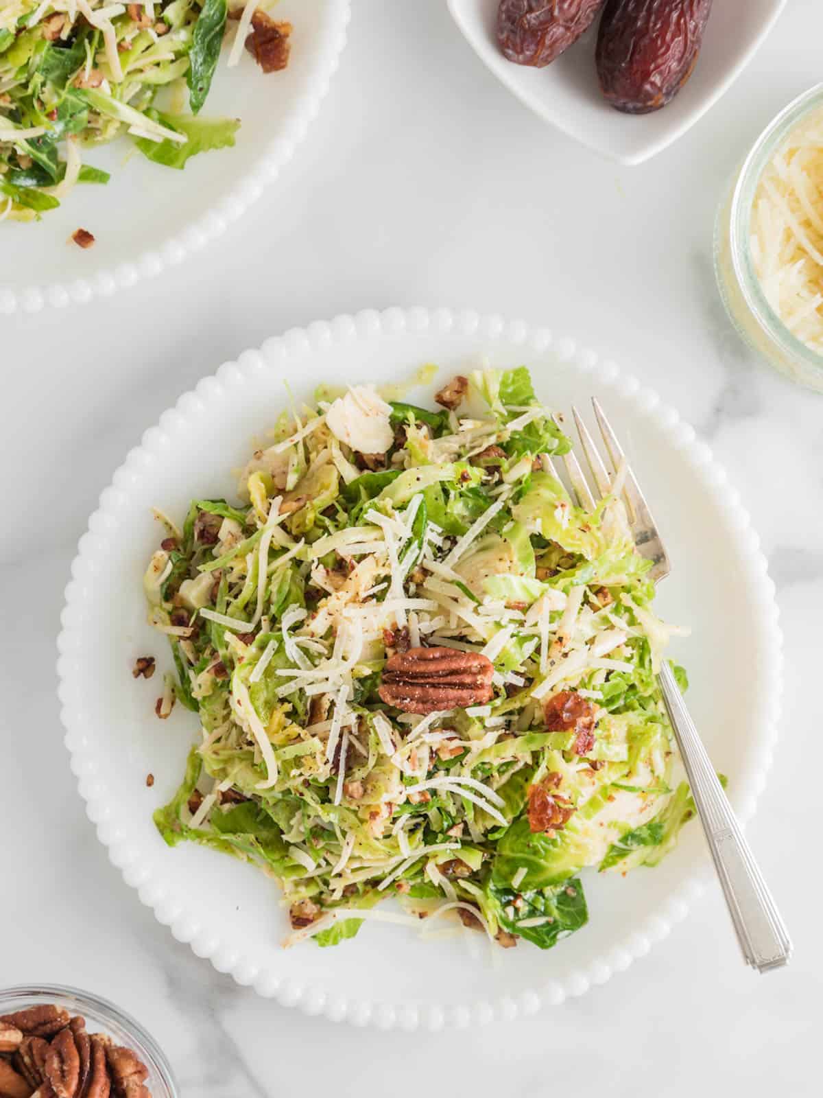 Plated serving of shredded Brussels sprouts salad with parmesan and mustard vinaigrette.