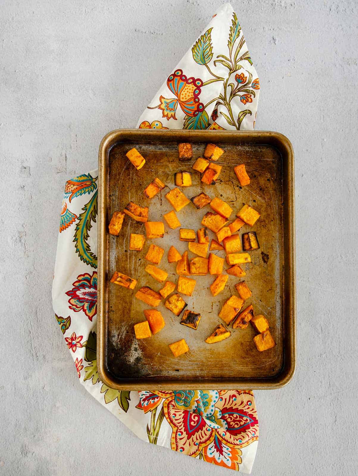 Roasted cubes of butternut squash on a baking sheet.