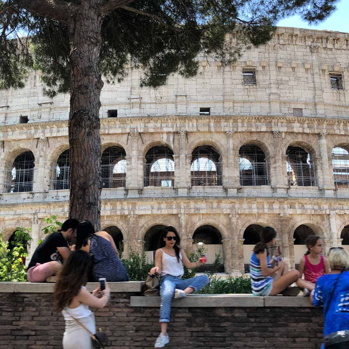 People sitting outside the the Roman Colosseum building.