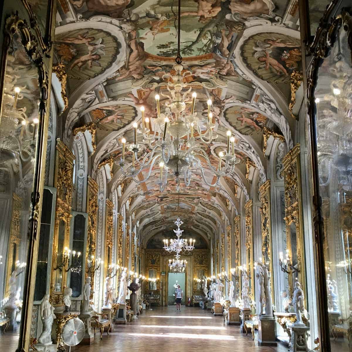 Lavish hallway with chandeliers, statures, and ornate murals at Doria Pamphilj Galleria