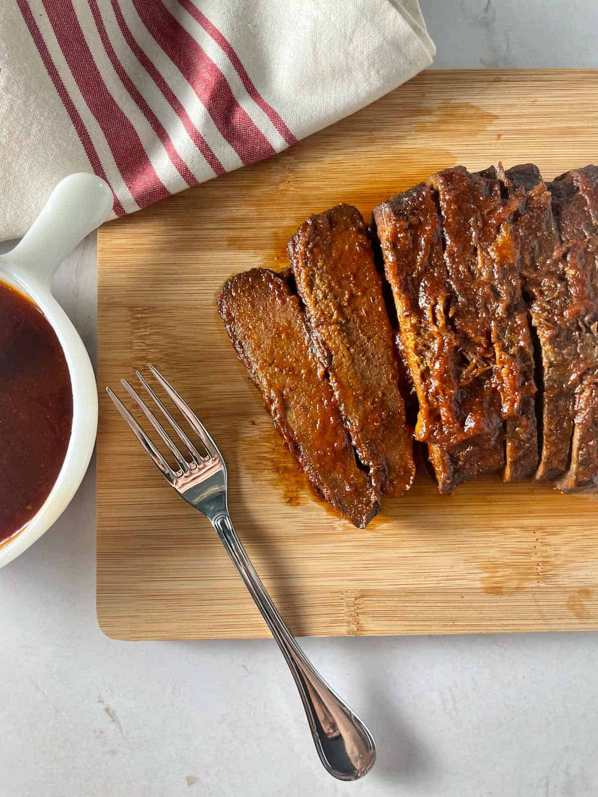 Slow cooked BBQ beef brisket sliced on a cutting board.