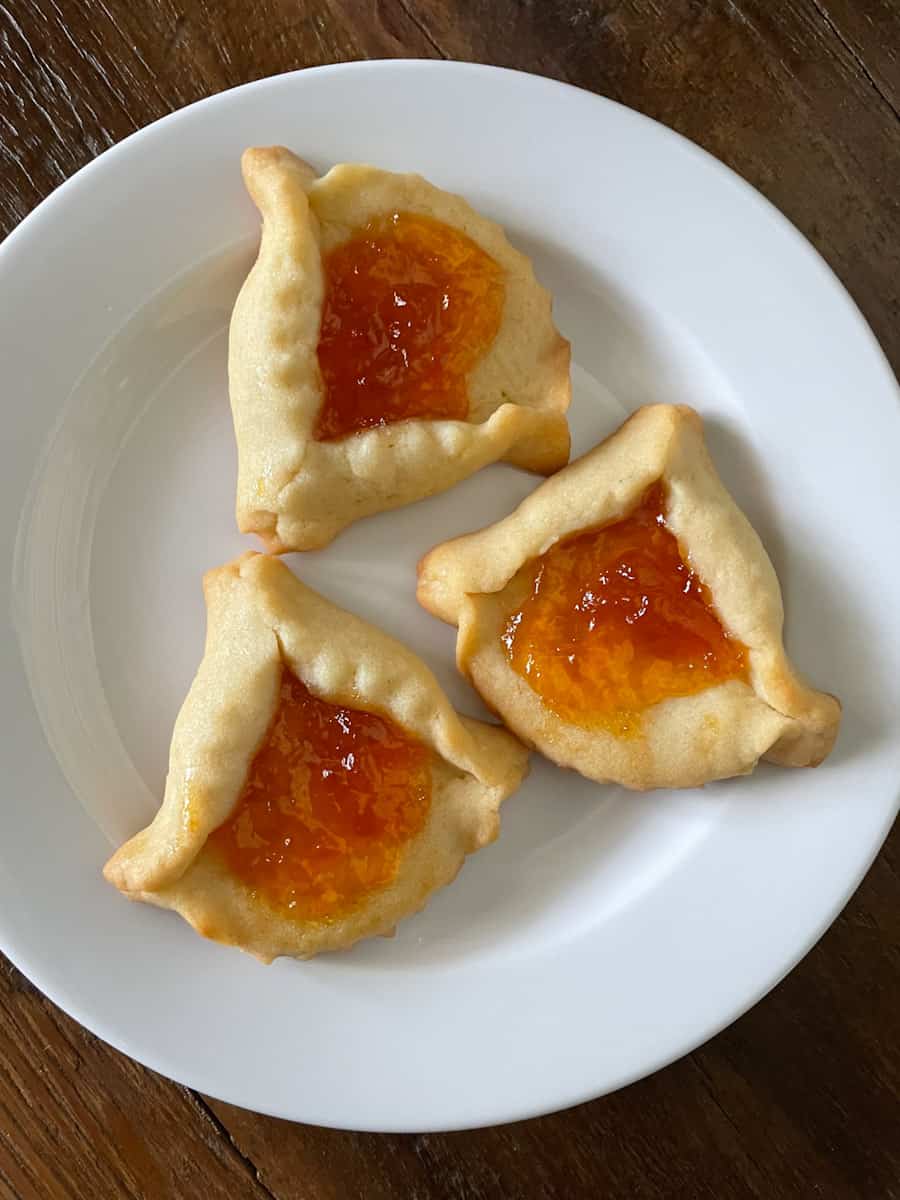Three opened Hamantaschen cookies with apricot jam.