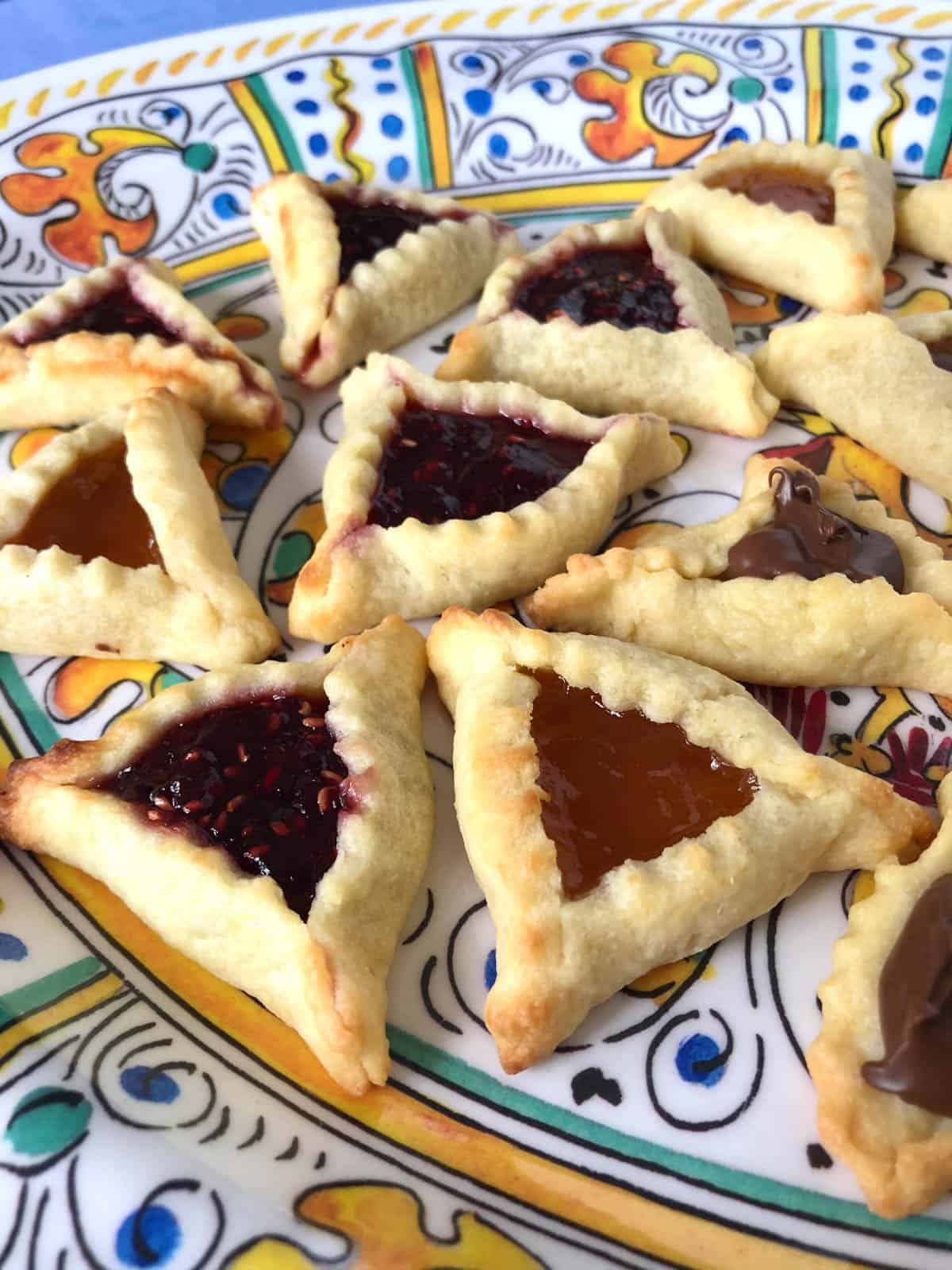 Several flavors of hamantaschen on a plate.
