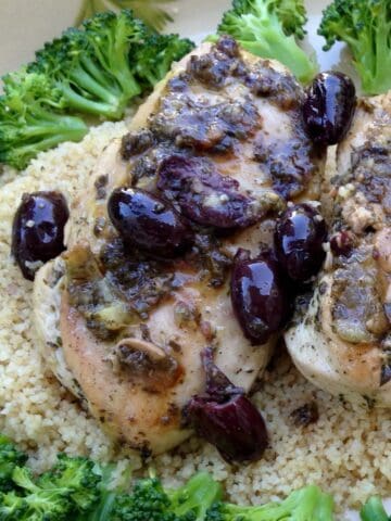 Italian herb chicken on a plate served with broccoli and couscous.
