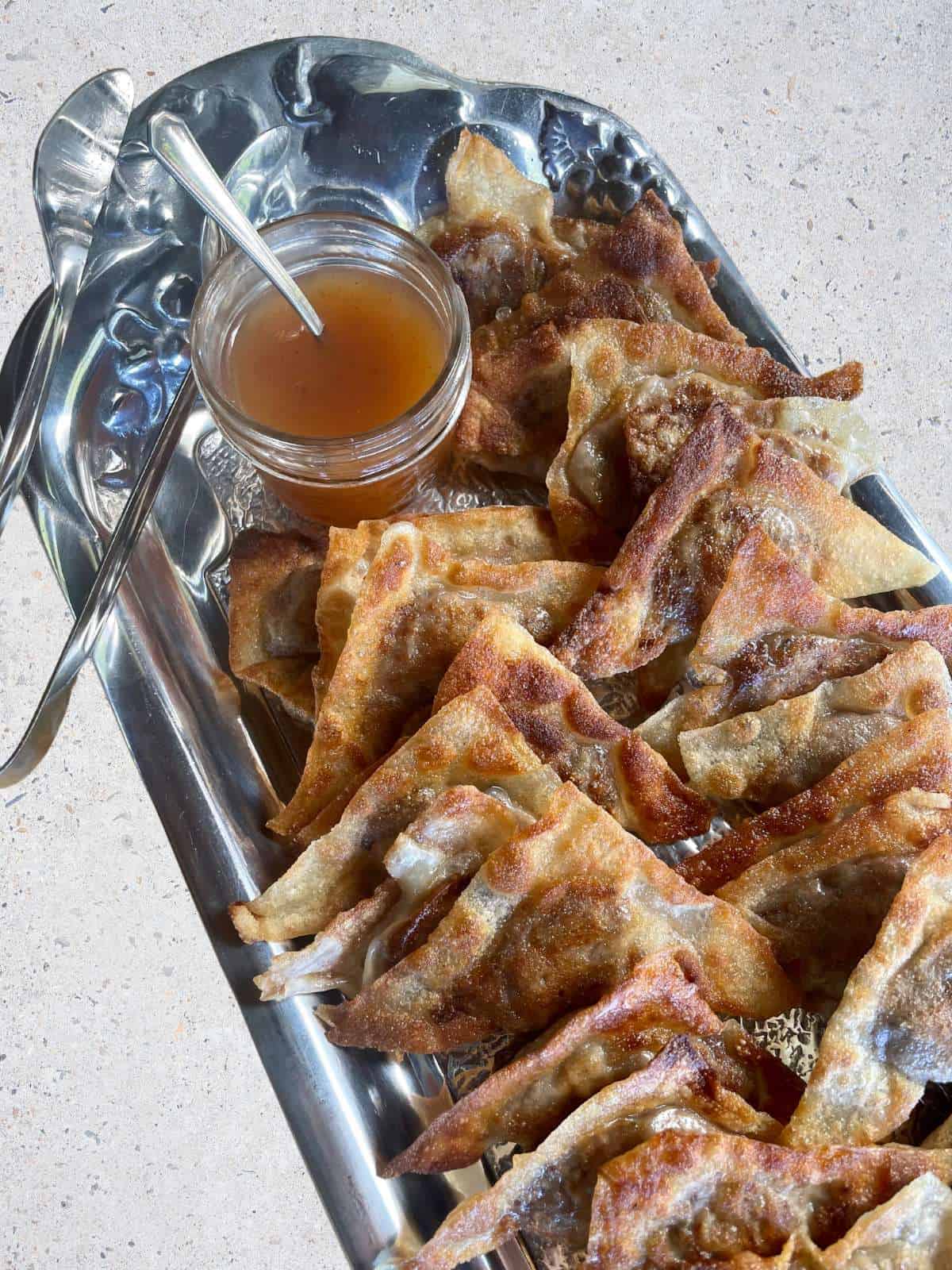 Fried kreplach with apricot dipping sauce on a silver platter.