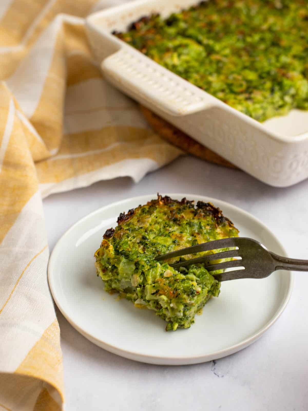 A fork cutting into a serving of broccoli kugel.