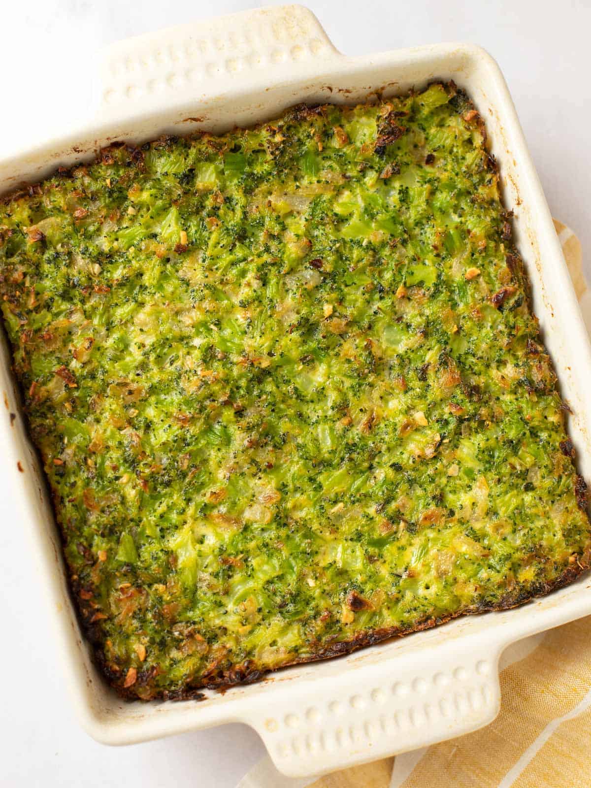 A square baking dish of broccoli kugel with a golden brown top.
