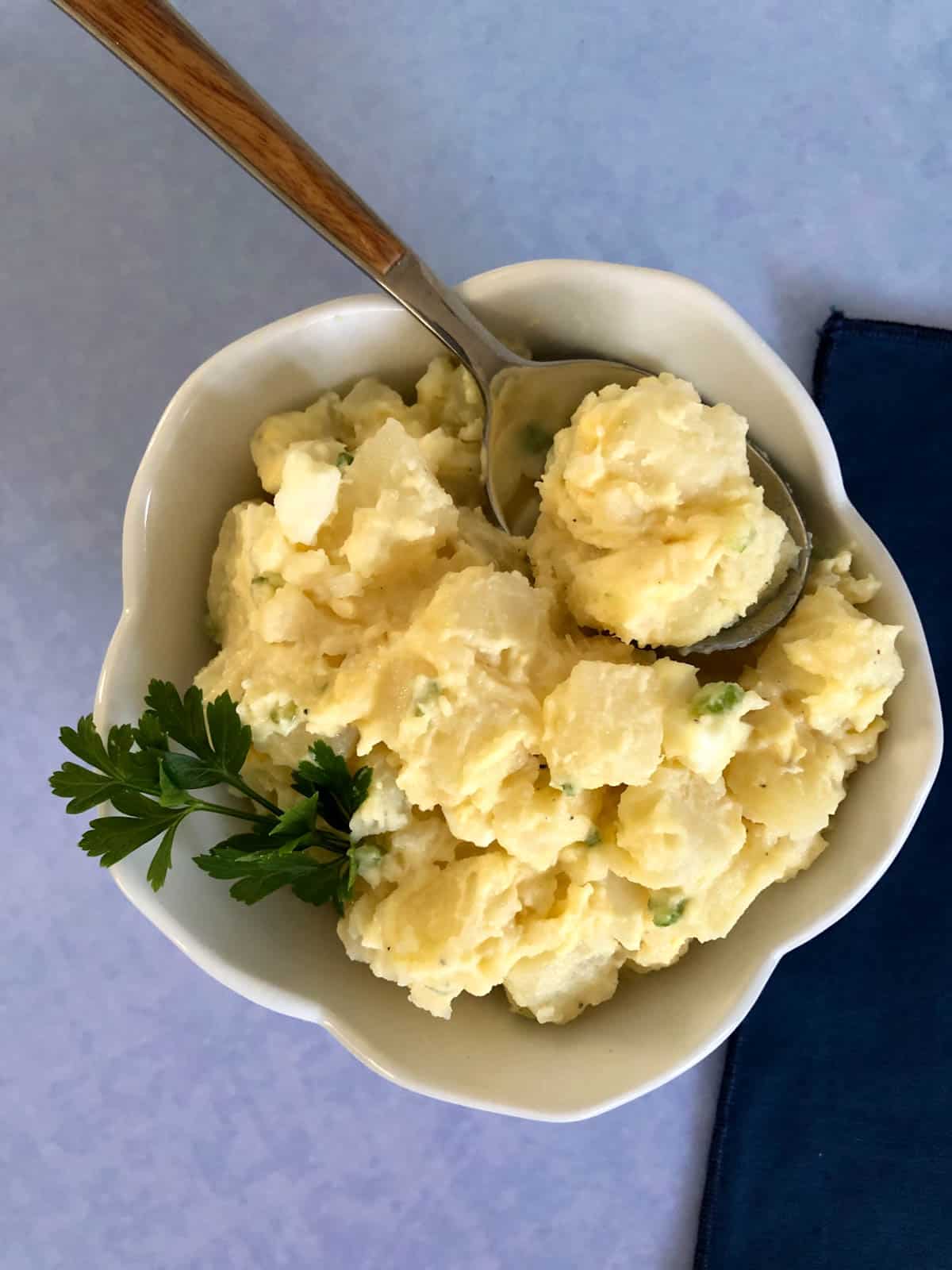 Potato salad in white bowl with blue background.