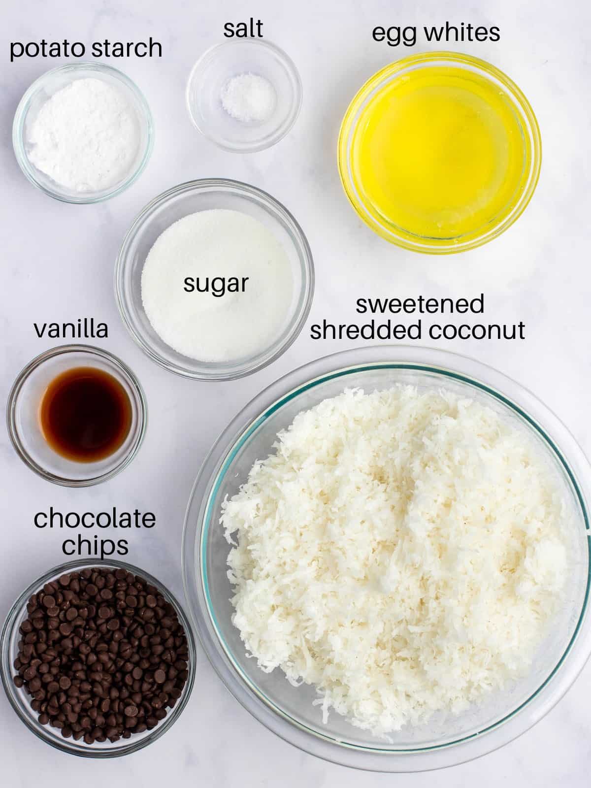 Ingredients for chocolate chip coconut macaroons in glass bowls.