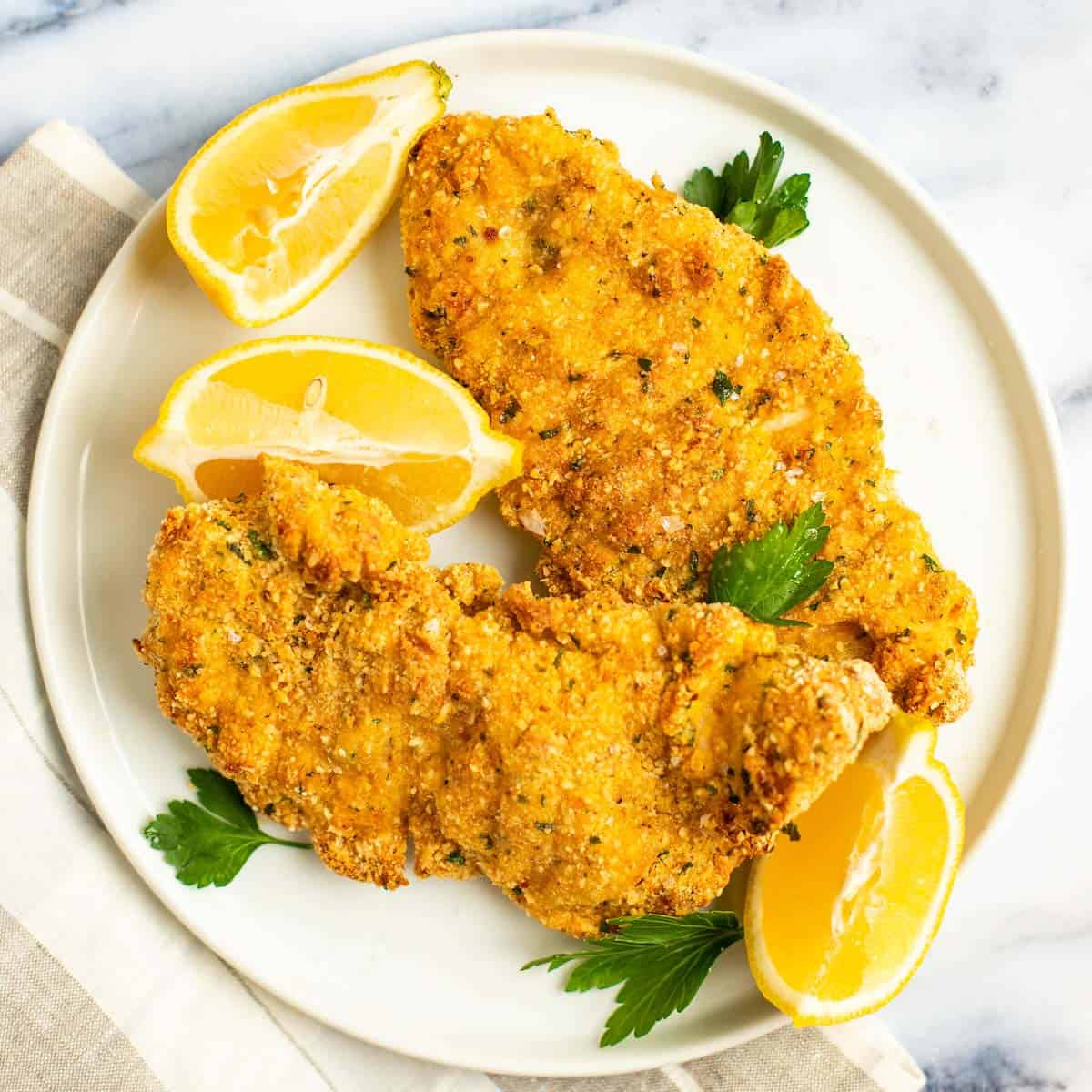 Crispy chicken schnitzel for Passover on a plate with lemon and parsley.