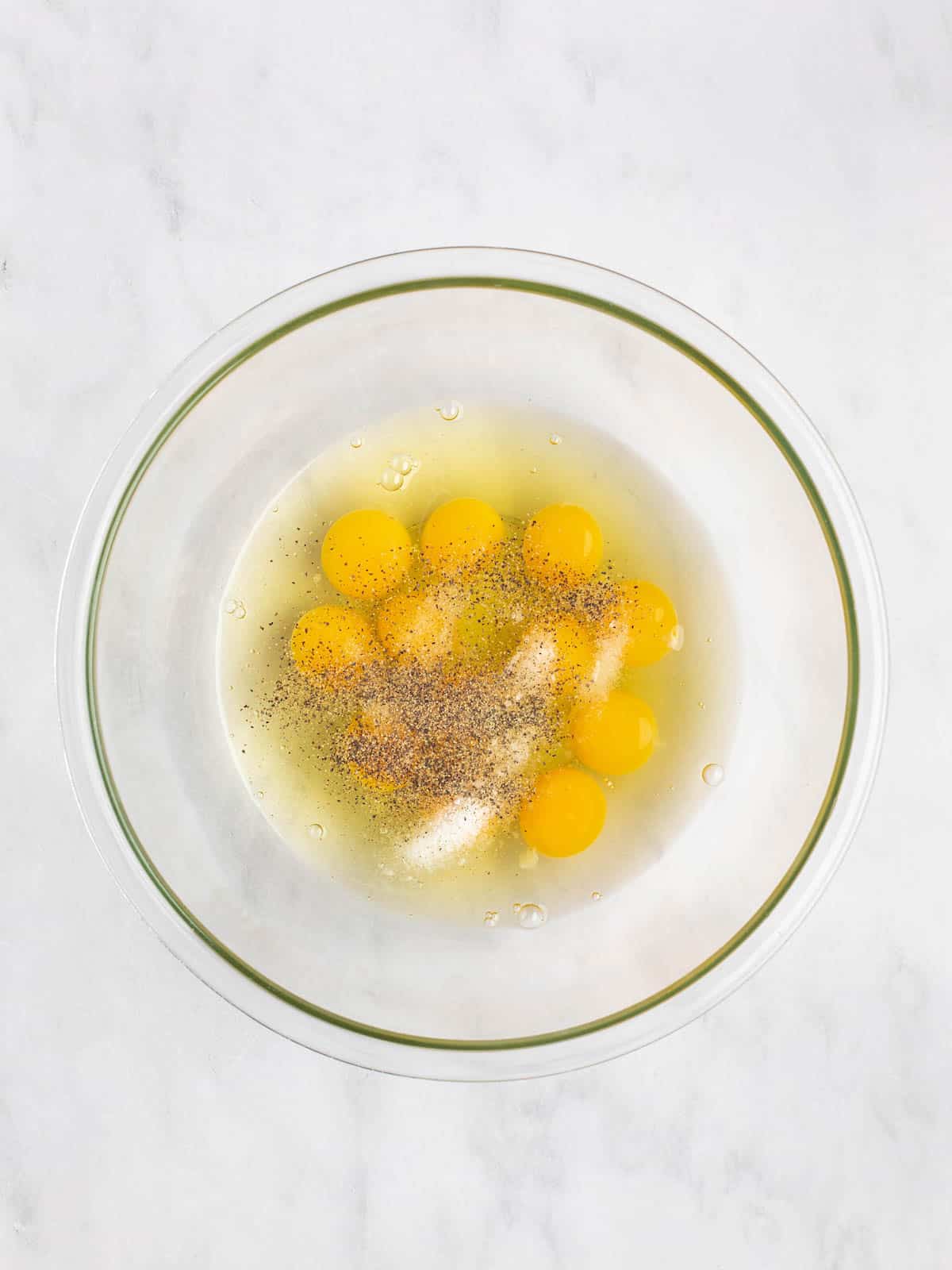 Eggs, salt, and pepper in a large glass bowl.