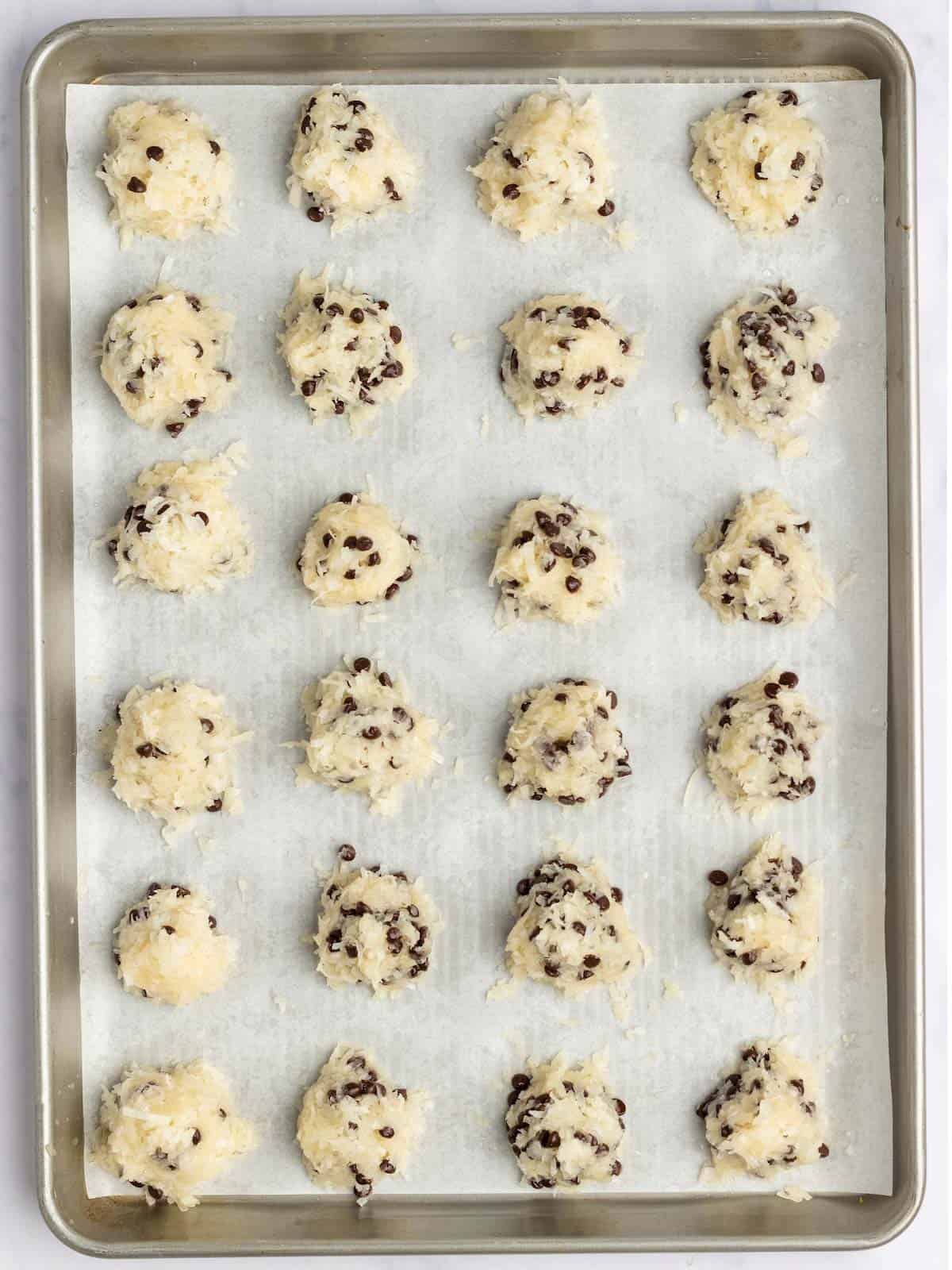 Cookie batter scooped into rounds and placed in rows on cookie sheet waiting to be baked in the oven.
