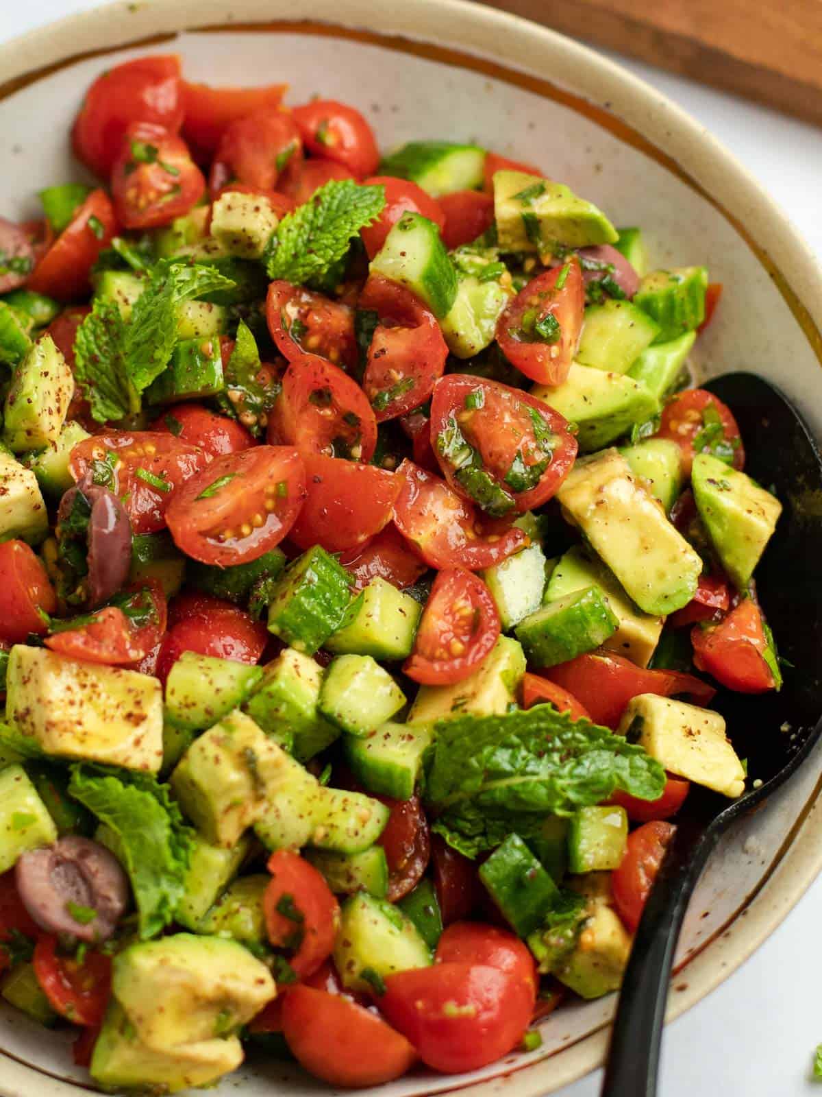 Up close view of Jerusalem salad with tomatoes, cucumbers, avocado, and fresh herbs.