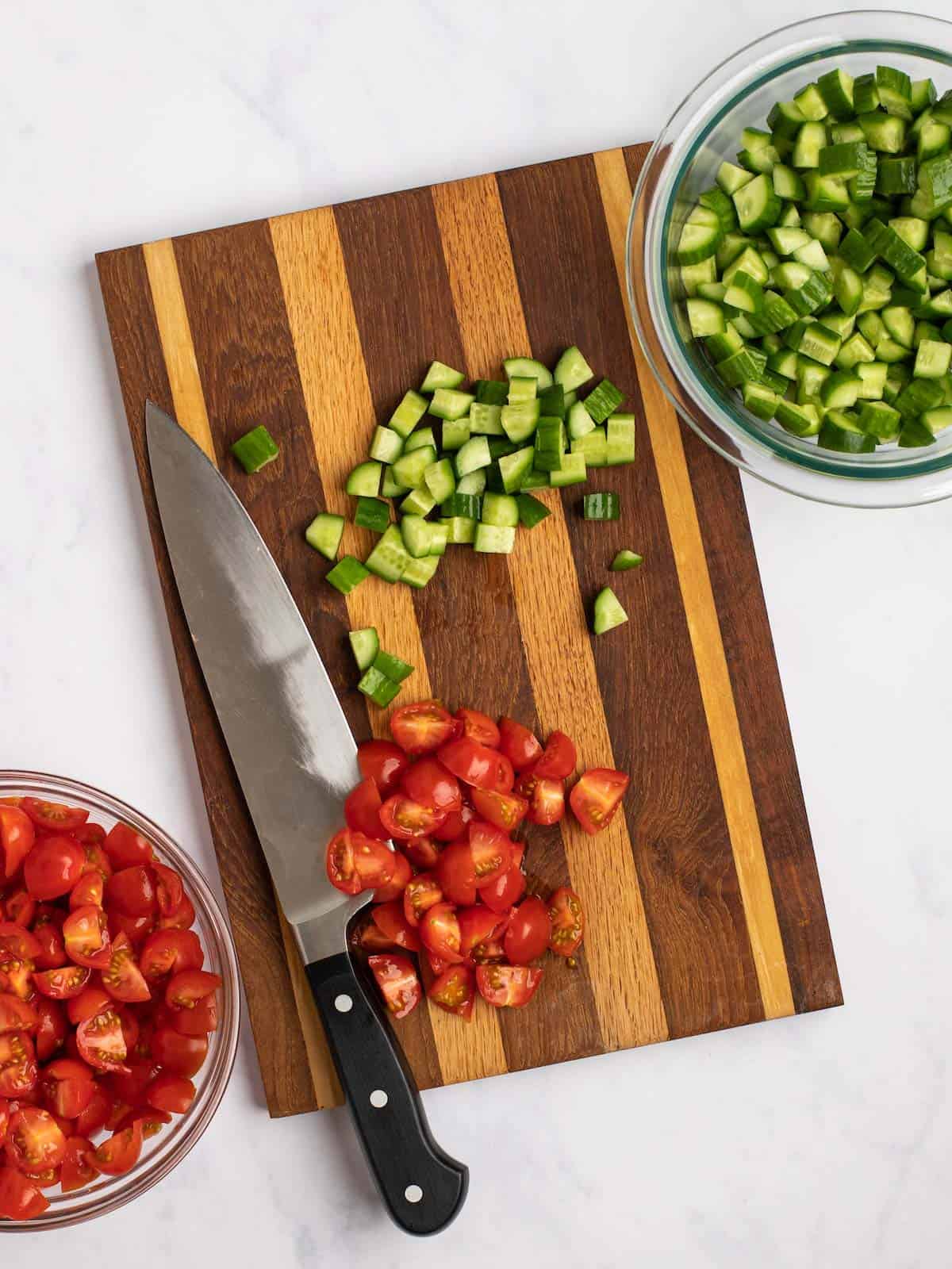 Chopped tomatoes and cucumbers on a chopping board.