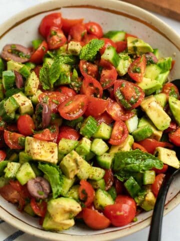 Colorful Israeli salad with tomatoes, cucumbers, avocado, and fresh herbs.