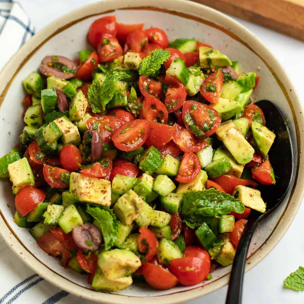 Colorful Israeli salad with tomatoes, cucumbers, avocado, and fresh herbs.