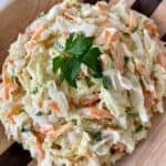 A bowl of coleslaw with cabbage, carrots, and green onions.