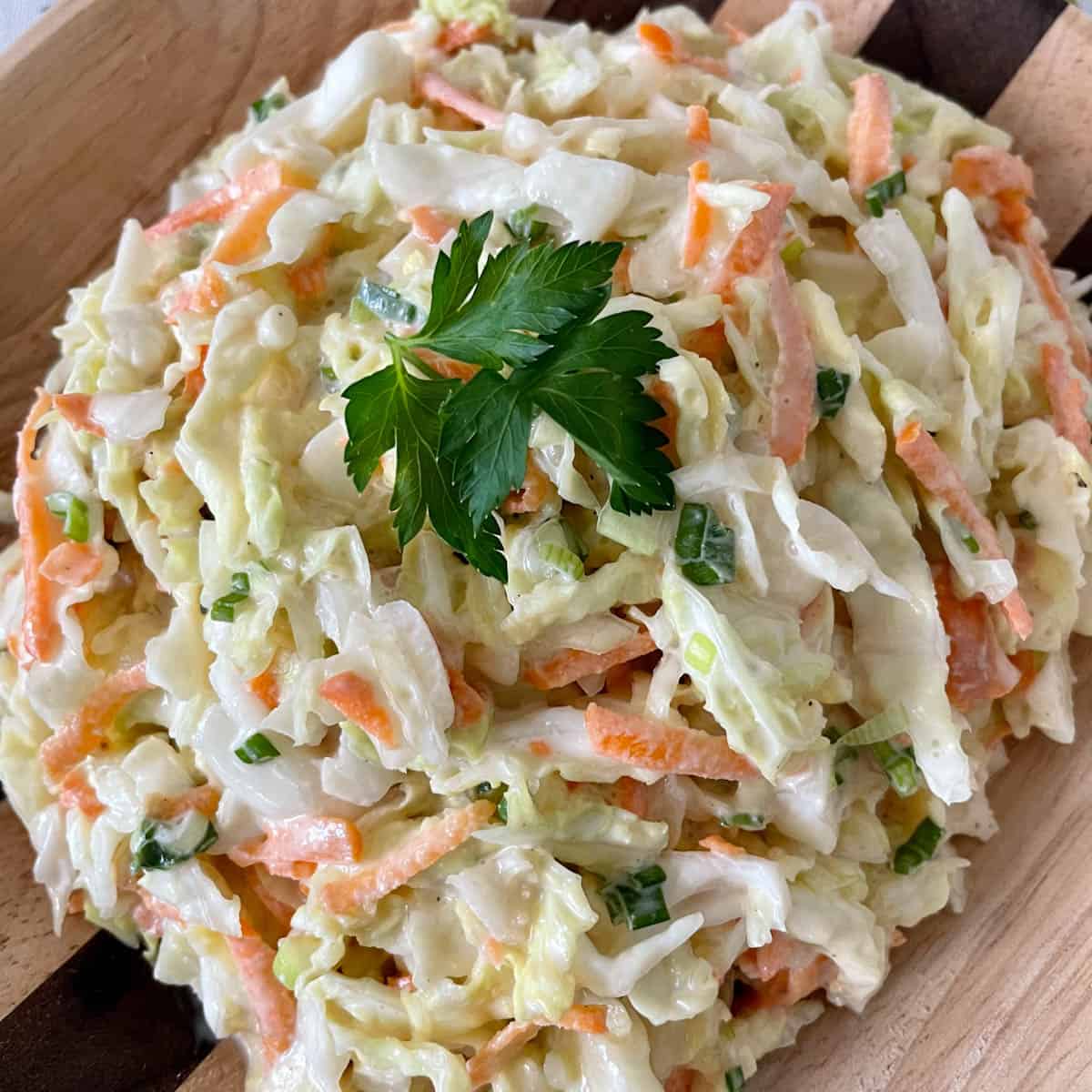 A bowl of coleslaw with cabbage, carrots, and green onions.