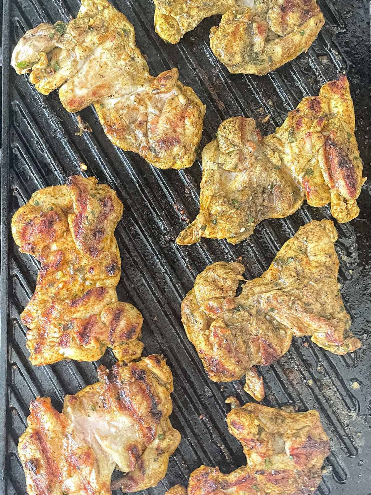 Grilled Israeli chicken thighs on a grill pan.
