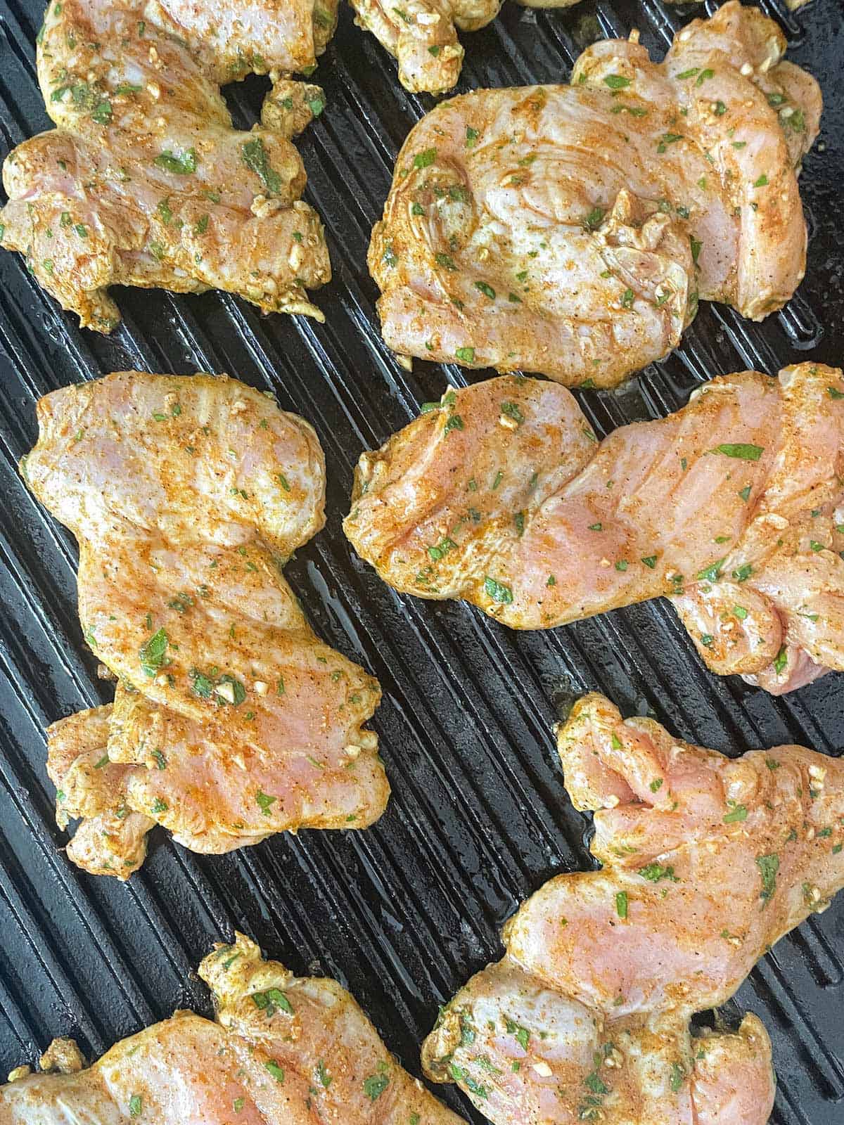 Grilled chicken thighs with mediterranean spices on a grill pan.