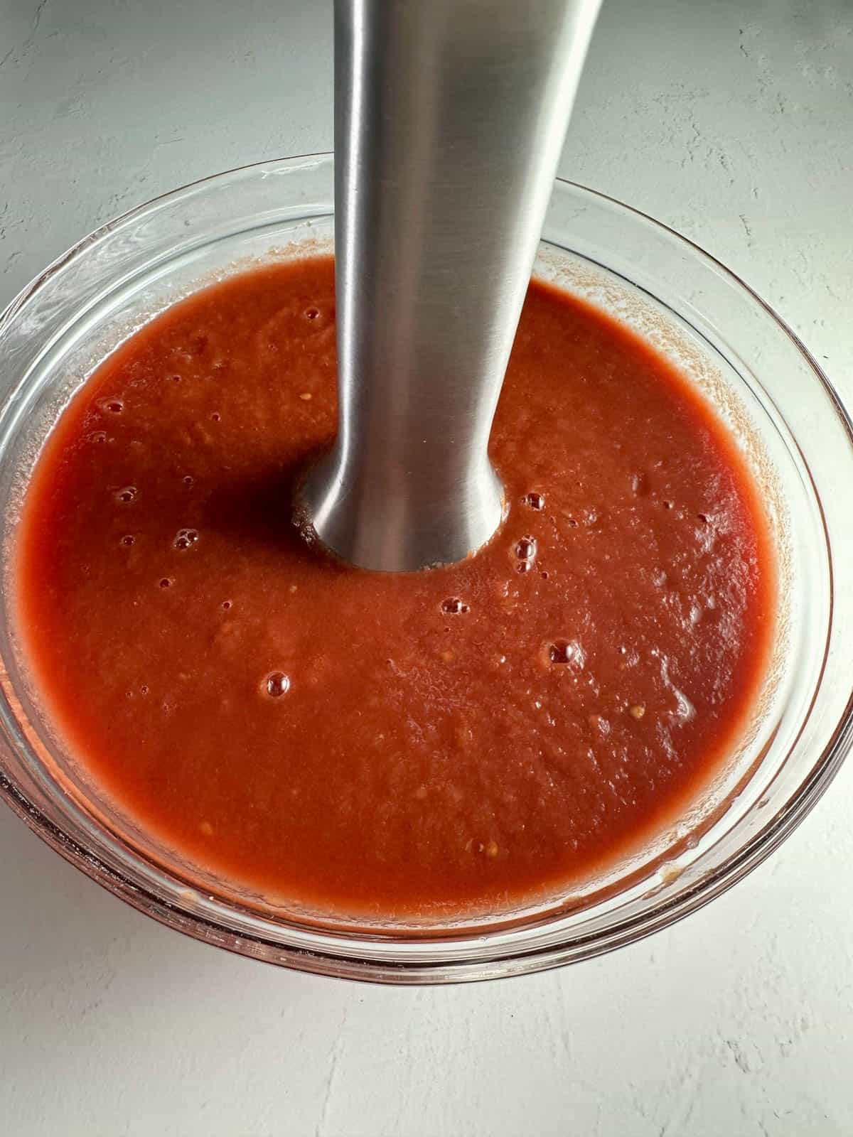 Using an immersion blender to puree tomatoes.