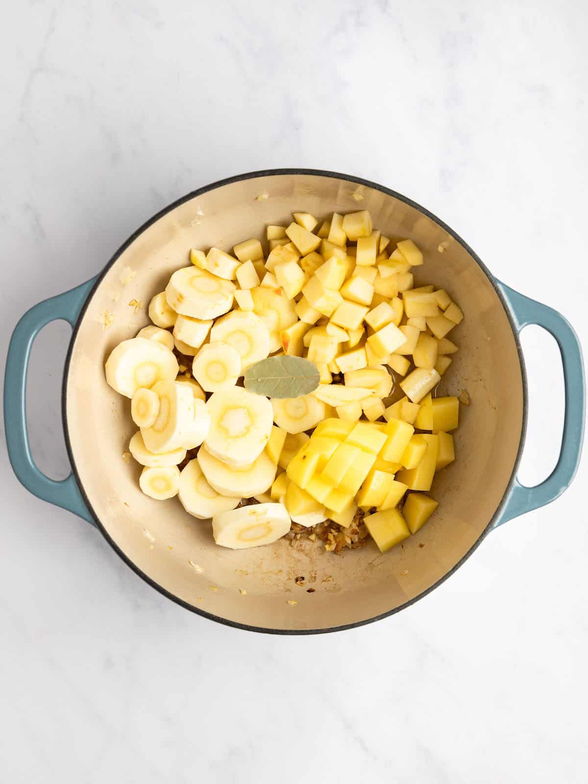 Potatoes, parsnips, and apples in a pot with seasonings.