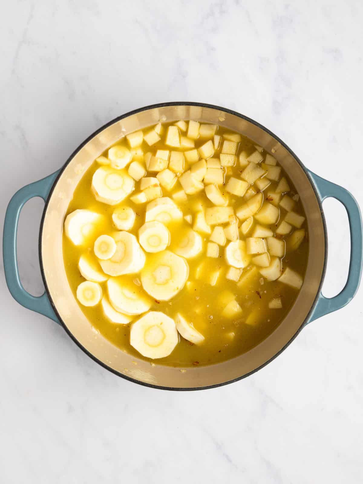 Potatoes, parsnips, apples, and broth in a large pot.
