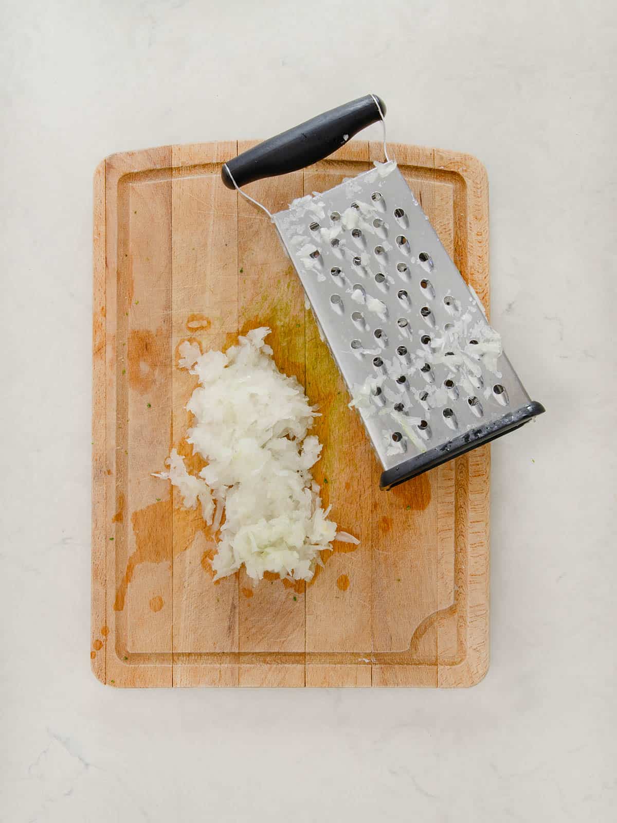 Grated onion with a box grated on a cutting board.