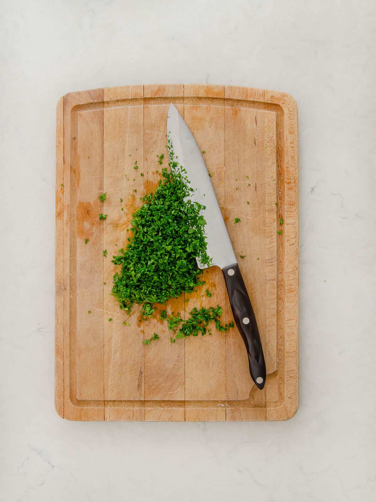 Chopped parsley on a cutting board with a knife.