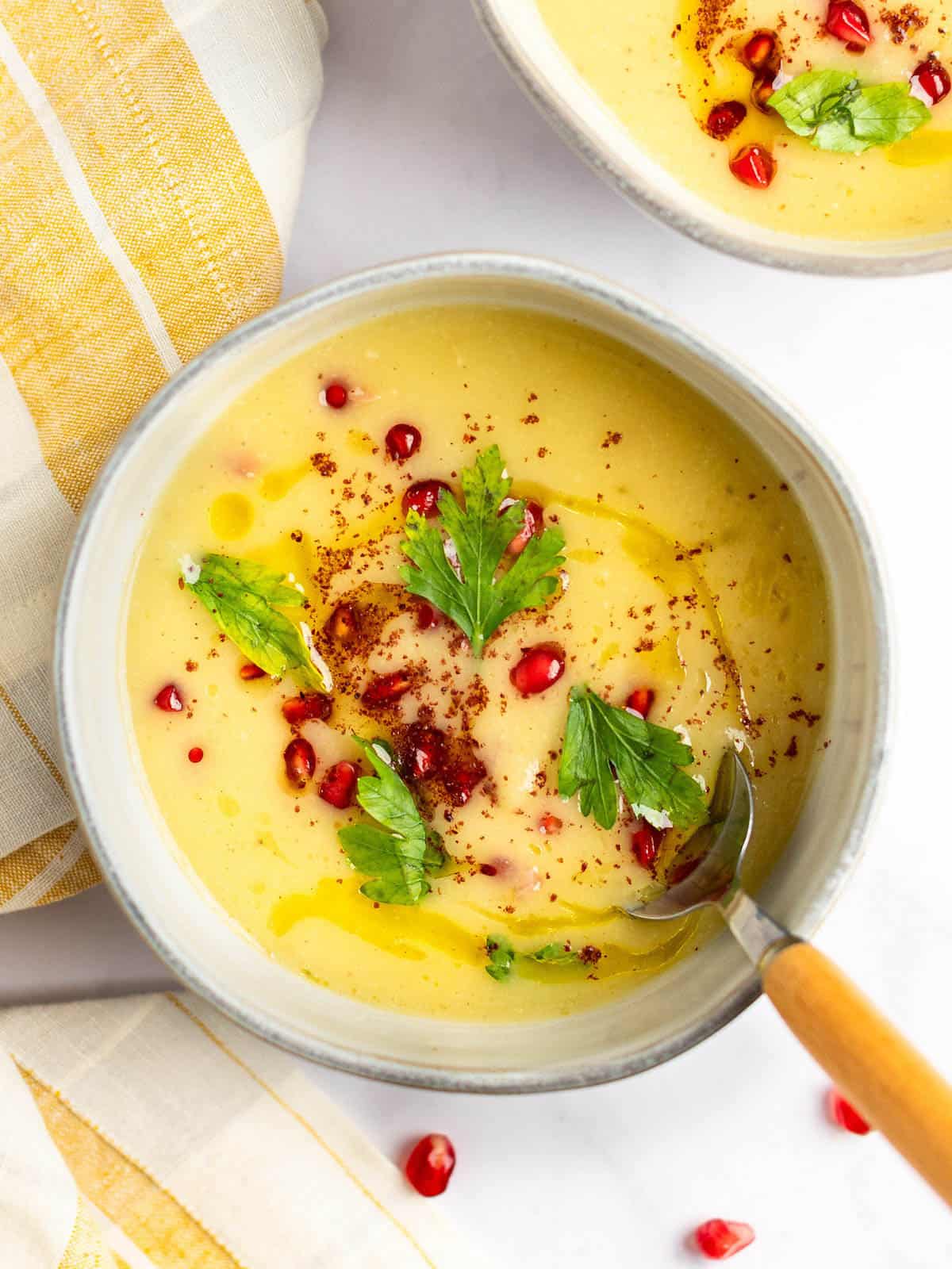 Parsnip and apple soup topped with pomegranate seeds in a bowl.
