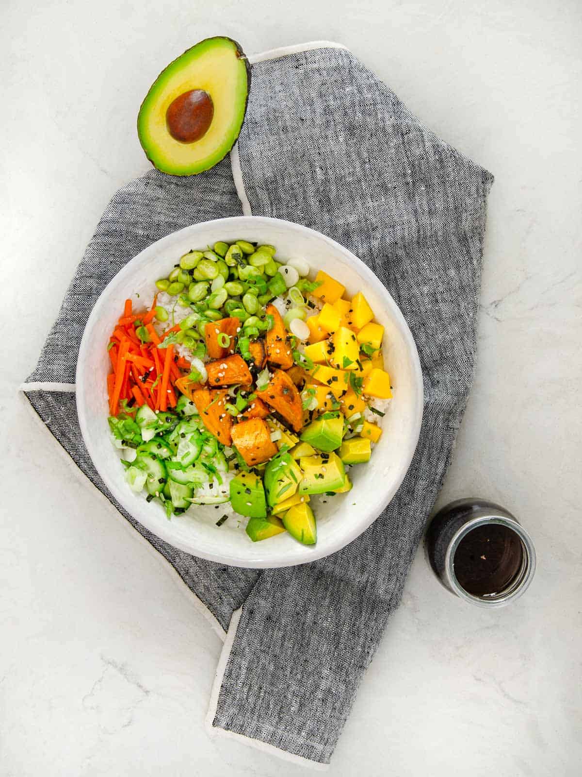Sushi salad bowl with carrots, avocado, sweet potatoes and edamame topped with furikake.