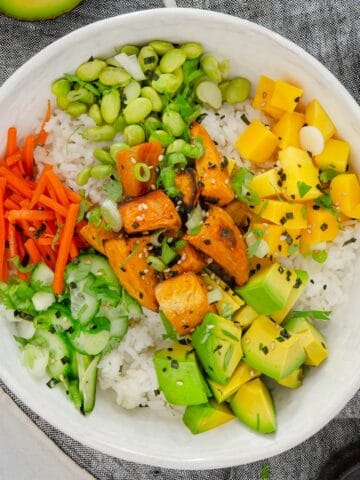 Deconstructed sushi salad with sweet potatoes, mango, carrots, cucumber, and edamame.