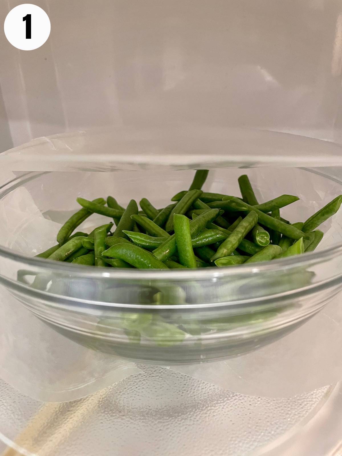 Green beans in a glass bowl in a microwave.