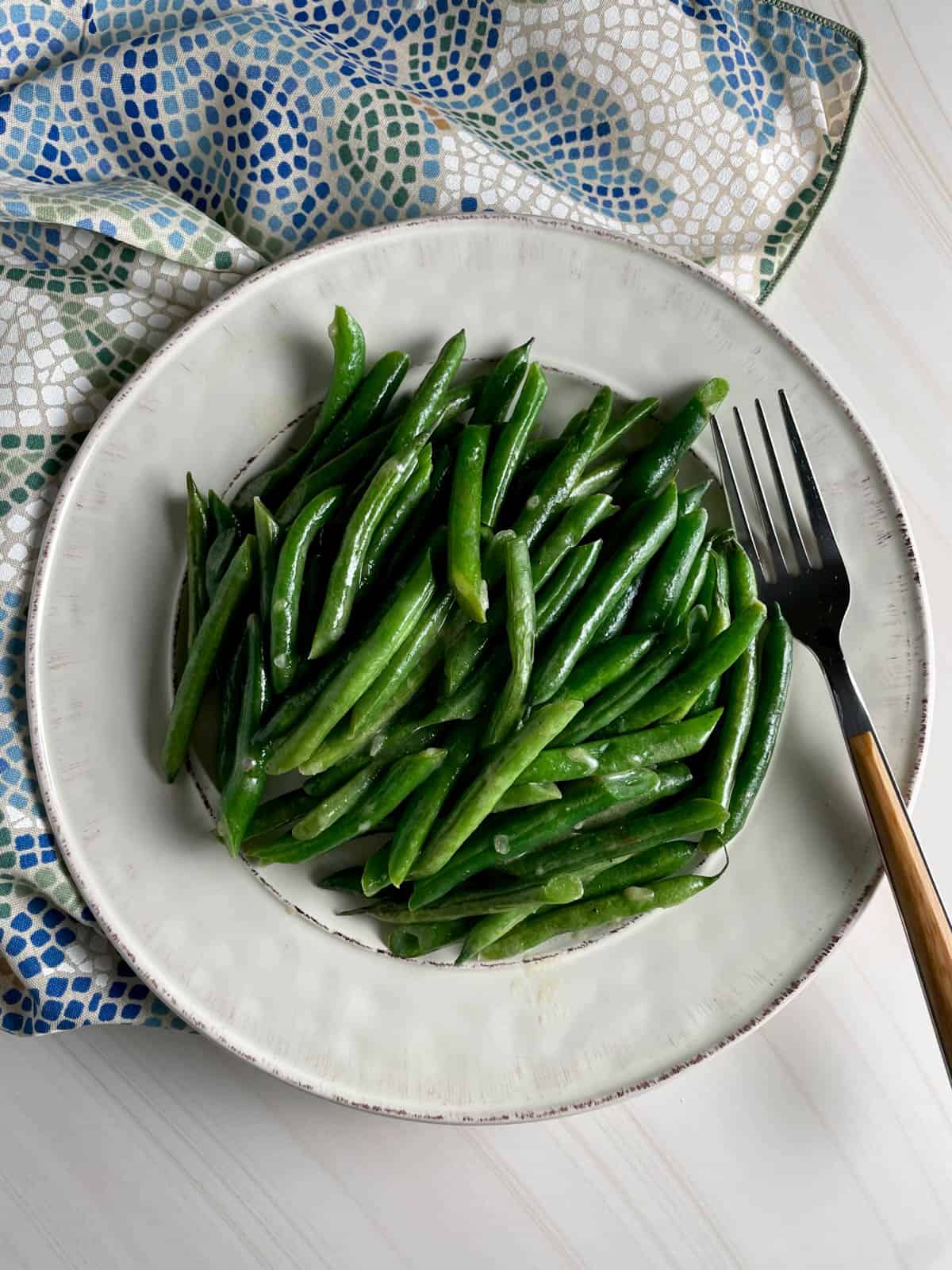 Plate of green beans with mustard sauce and a fork.